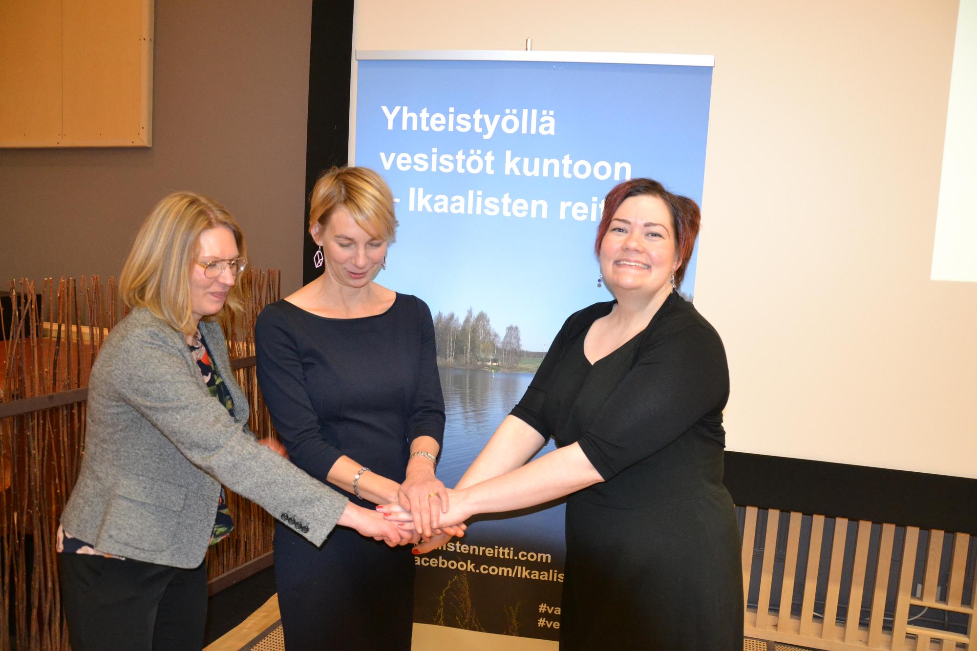 Pirkanmaan ELY-keskuksen vesiyksikön päällikkö Heidi Heino, vesitalousasiantuntija Anne Mäkynen ja projektsiasiantuntija Virve Rinnolla valokuvassa, taustalla Ikaalisten reitti -hankkeen juliste.